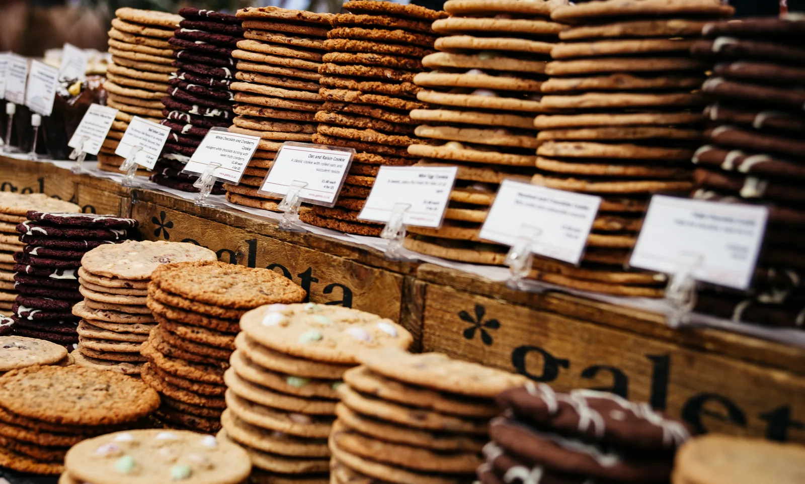 Stacks of cookies behind handwritten labels at a bakery counter