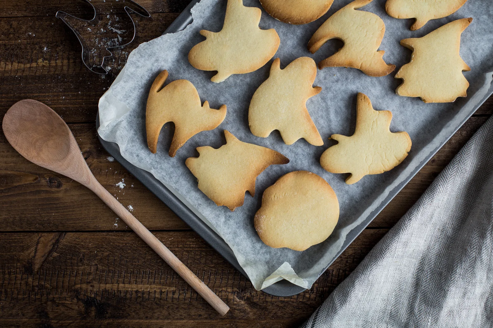 Cut-out cookies on a baking tray with a wooden spoon