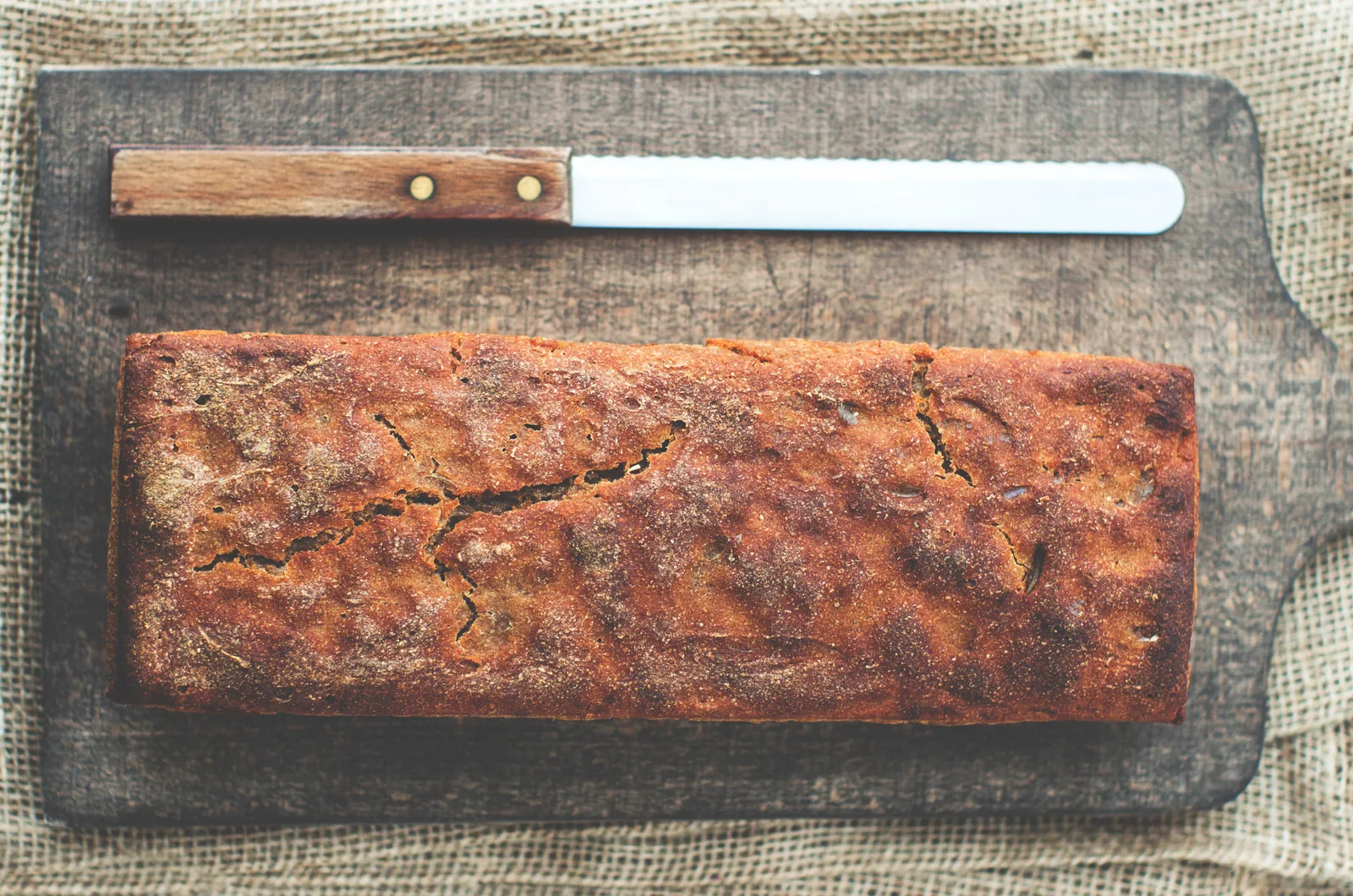 A loaf cake on a board with a bread knife